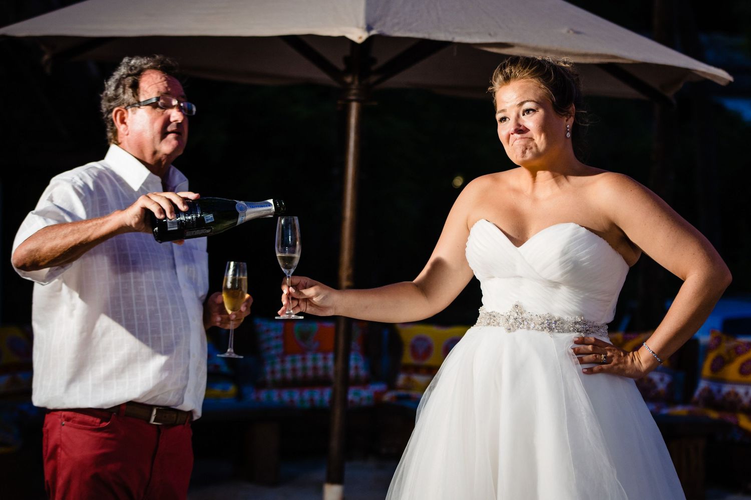 Wedding couples enjoying drinks and dancing under outdoor umbrellas at a daytime celebration.