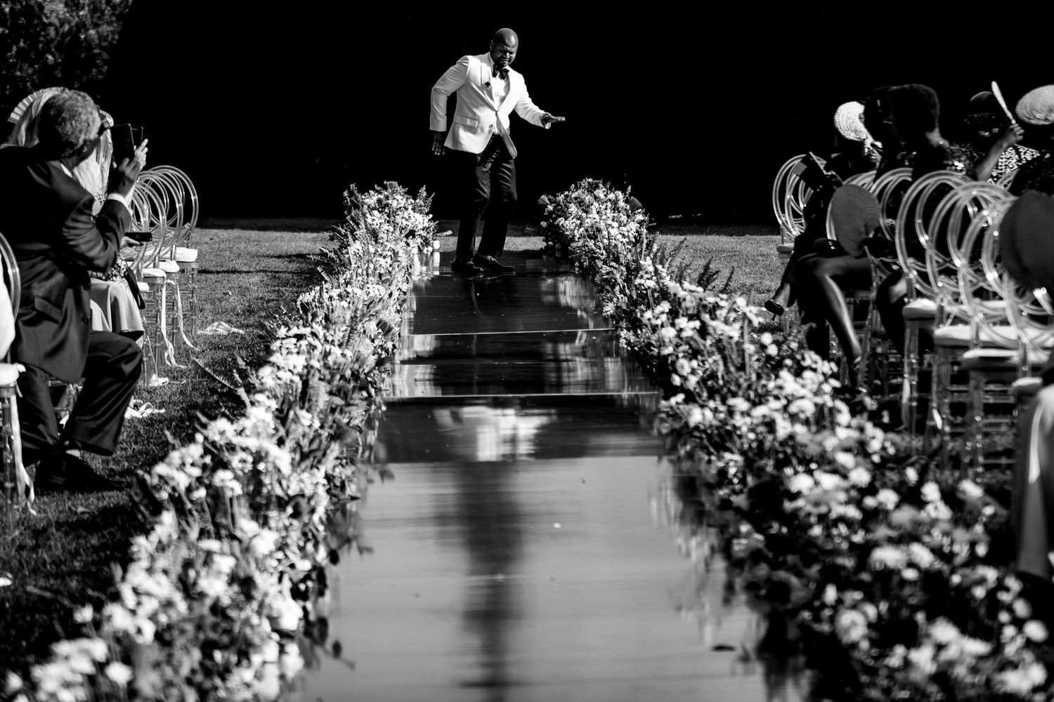 Elegant floral arrangements line an outdoor wedding ceremony aisle.