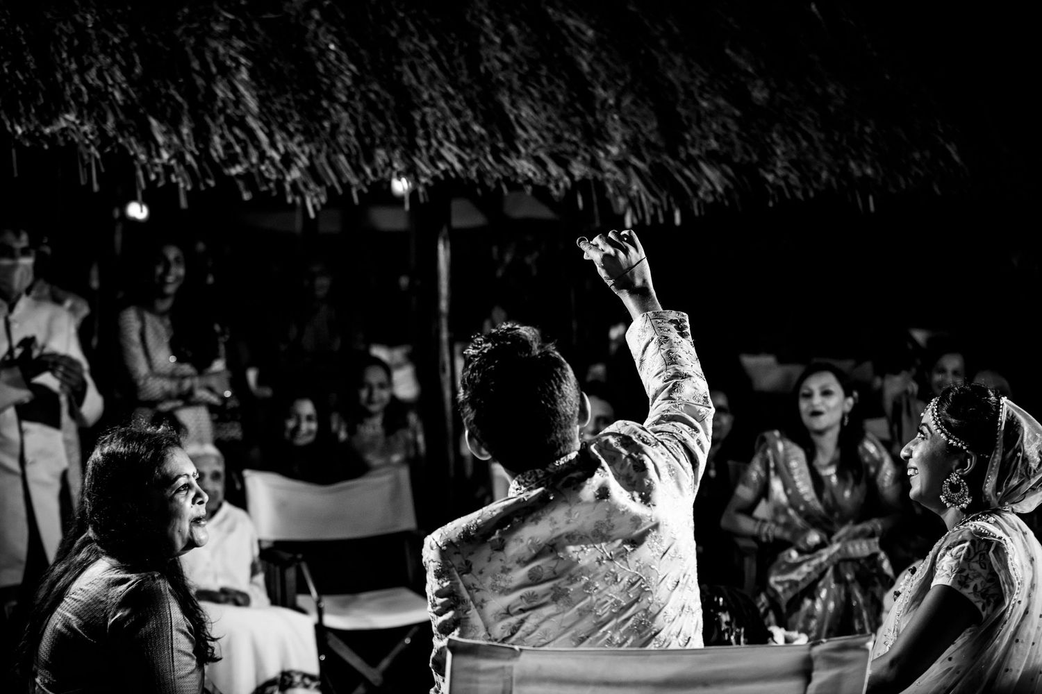 Black and white photograph of celebration with raised hands and crowd silhouettes.