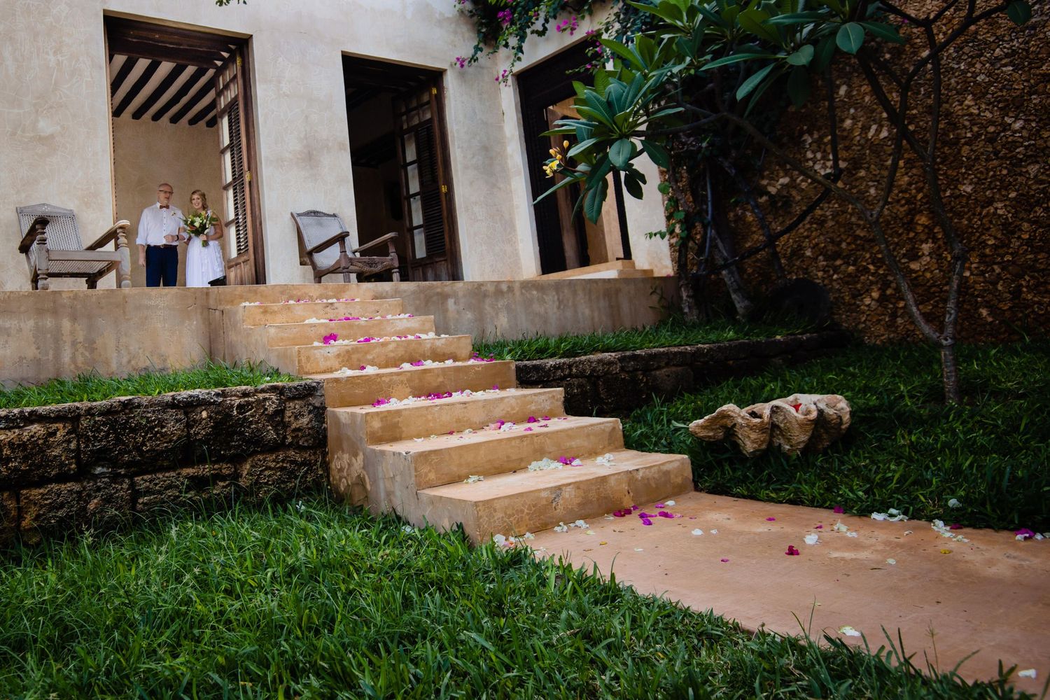 Stone patio with steps leading to a garden area surrounded by greenery.