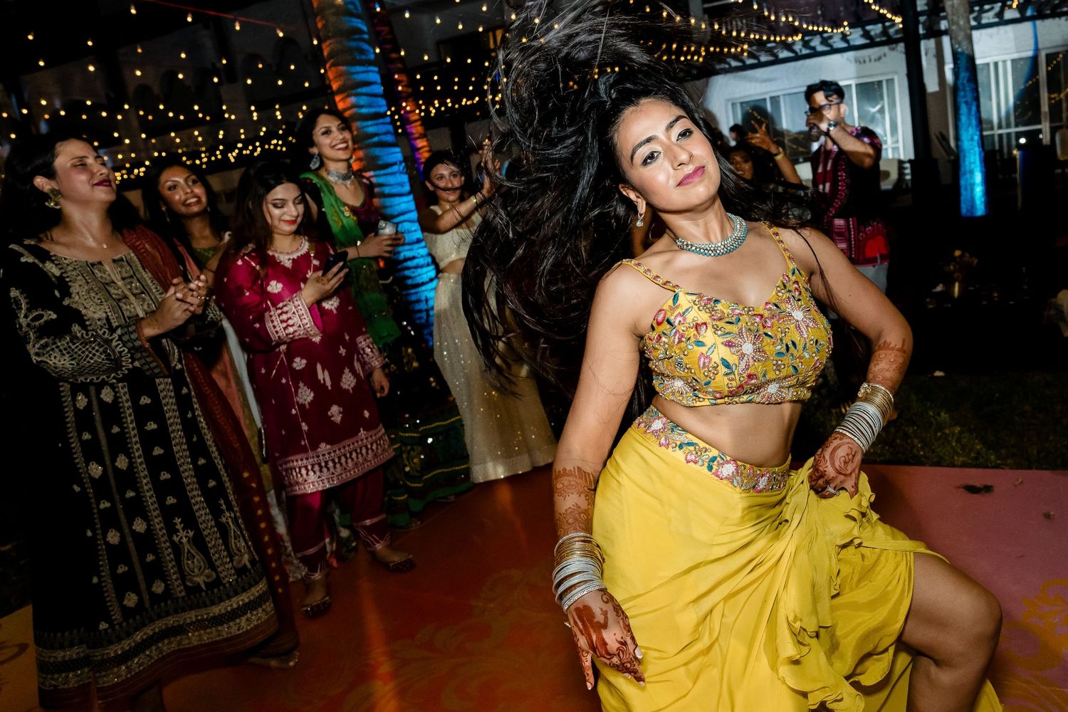 A dancer in yellow traditional attire performs at an evening celebration.