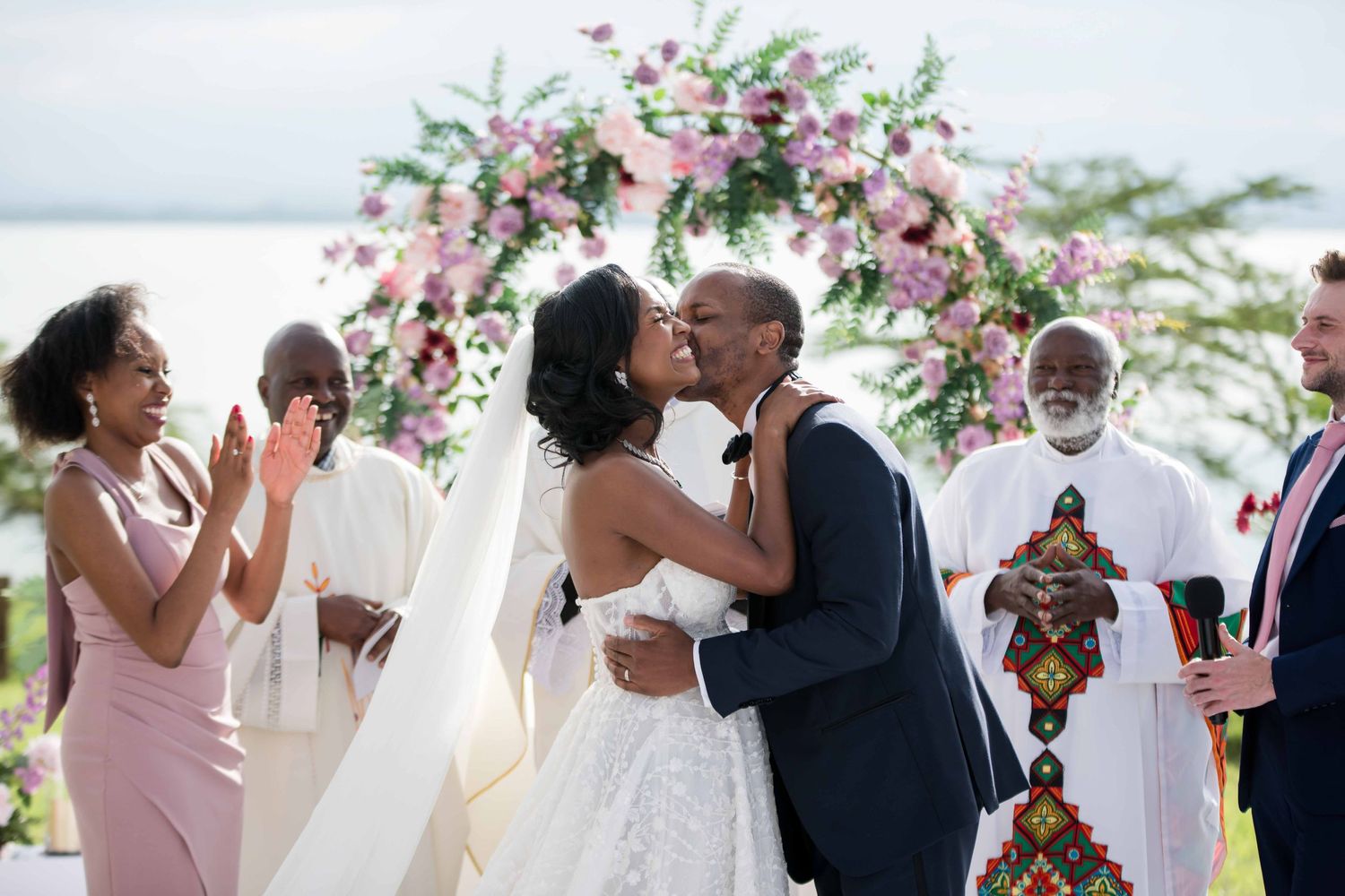 A joyous wedding celebration moment under a pink floral arch.