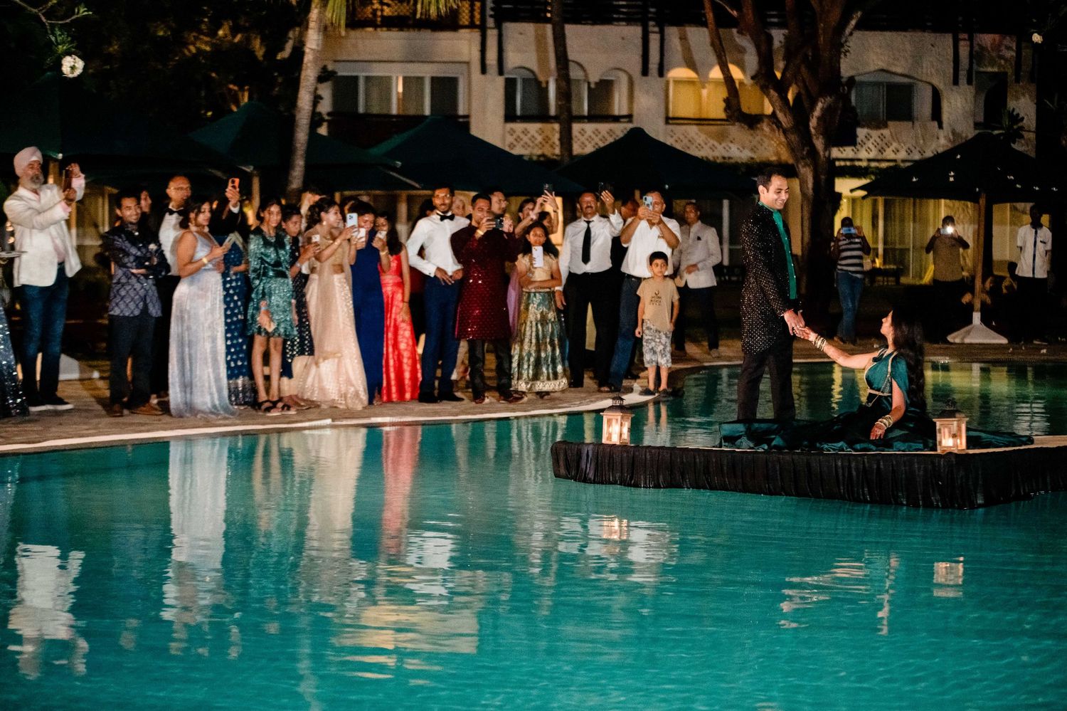 Wedding guests gathered around a swimming pool for an evening celebration.