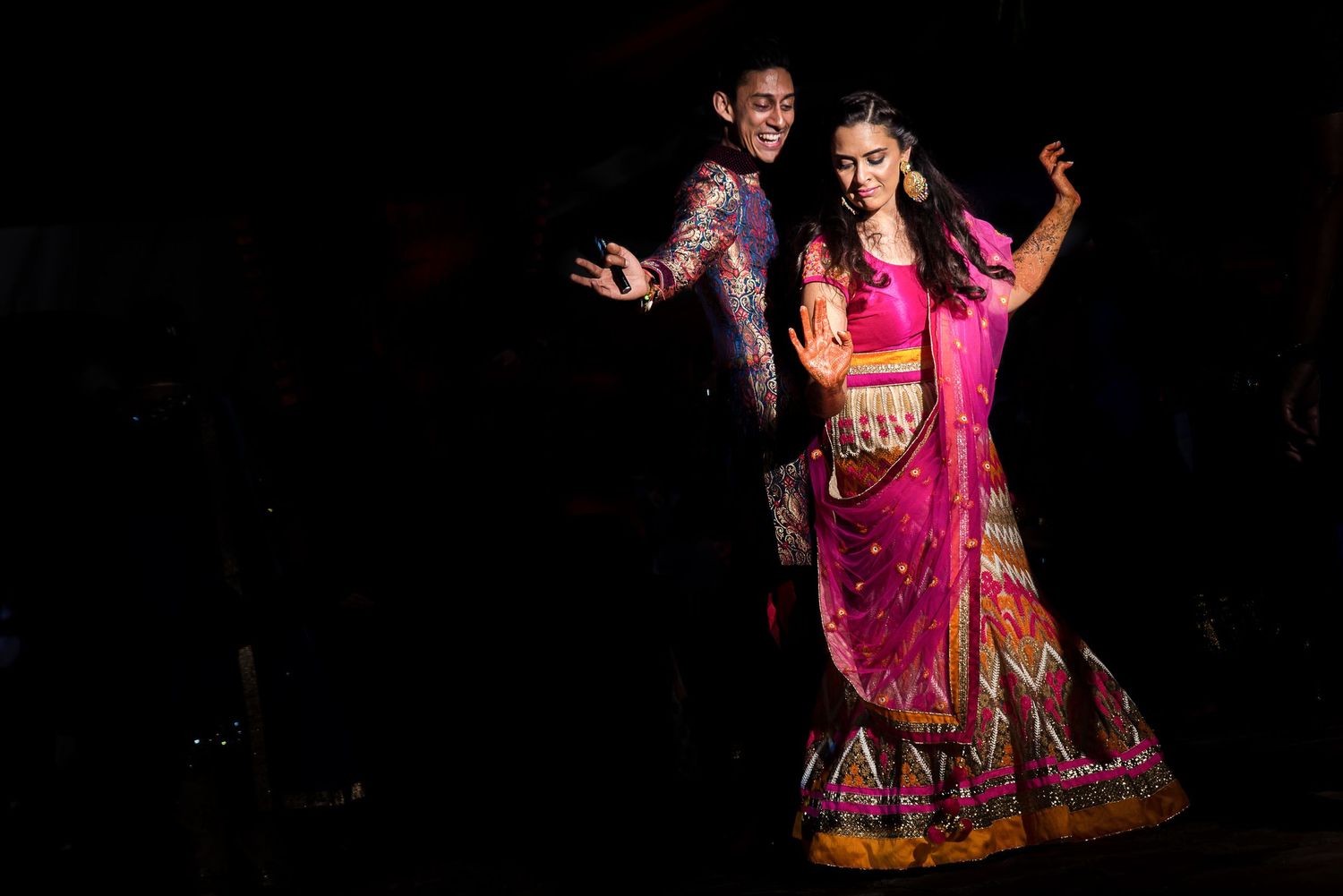 Traditional Indian dance performance with colorful costumes on dark stage.