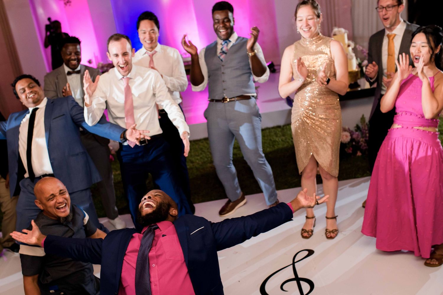Wedding guests dancing and jumping with enthusiasm on an illuminated dance floor.