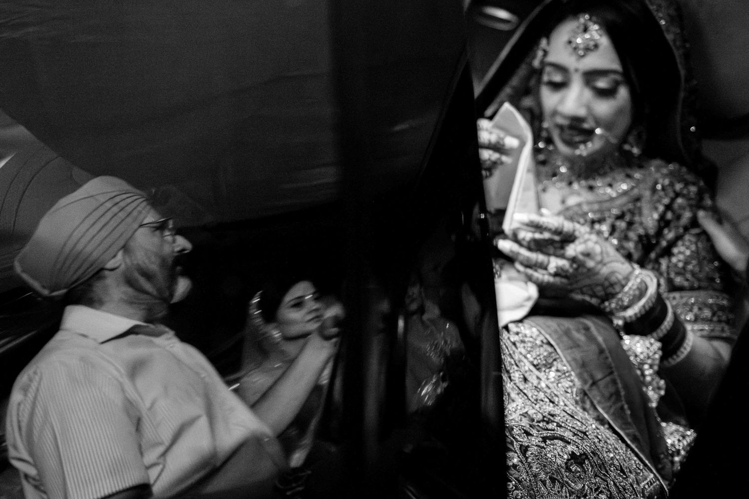 Black and white candid moment during traditional Indian wedding celebration.