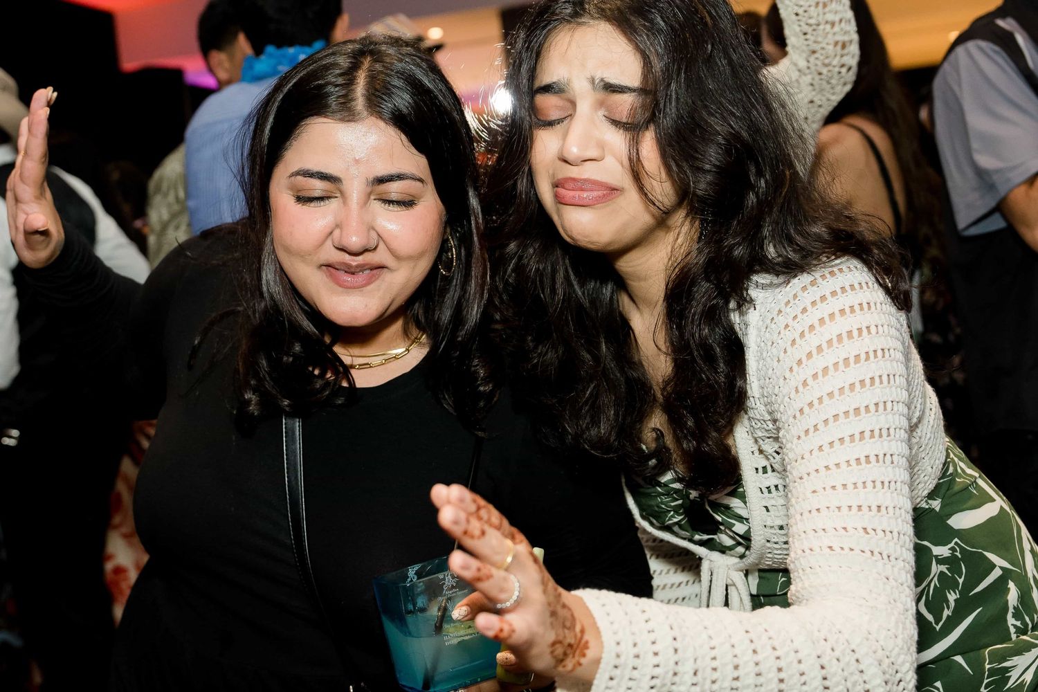 Two friends share a candid moment laughing together at a social gathering.