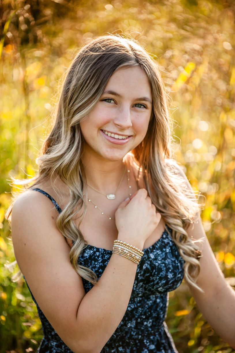 Golden hour senior girl in nature wearing a sparkly blue dress.