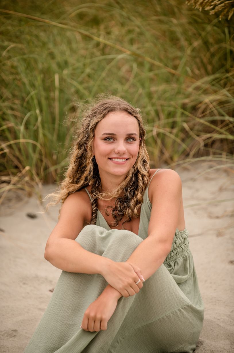 Senior girl portrait on sandy beach with sea grass background.