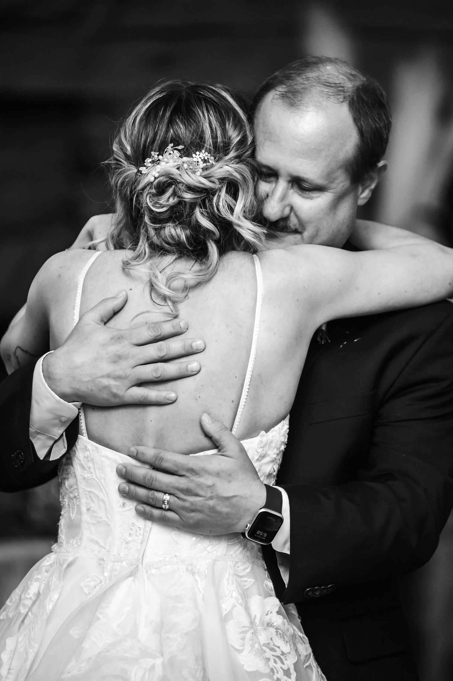 Black and white photo of a bride and groom sharing an emotional embrace during their first dance at a wedding.