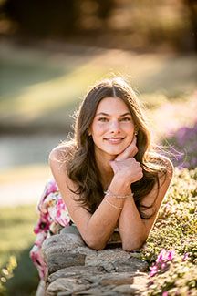 Artistic outdoor portrait of a senior girl with soft lighting and natural elements.