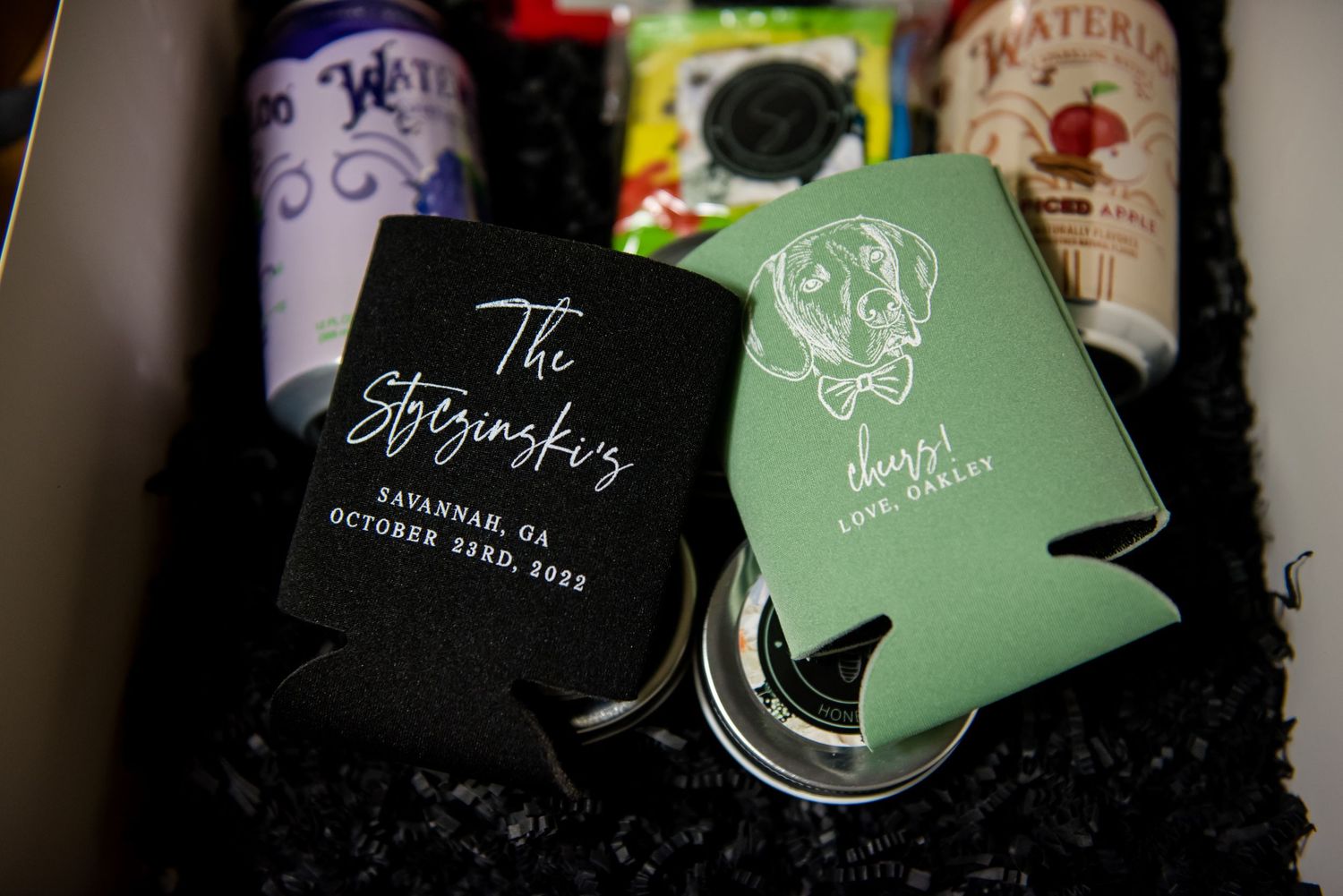 Custom wedding koozies in black and green with dog illustration in a gift box with shredded paper filler.