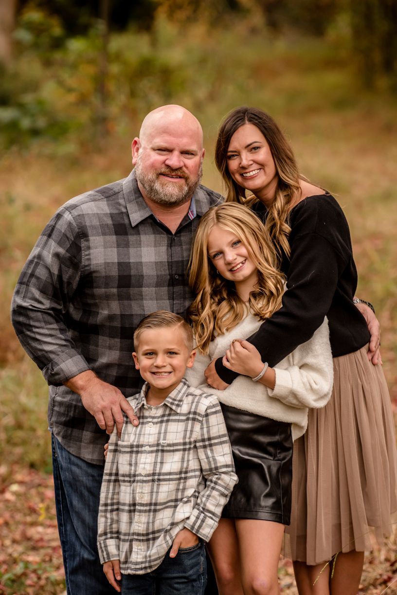 A group poses for an autumn portrait wearing coordinated plaid and neutral tones.