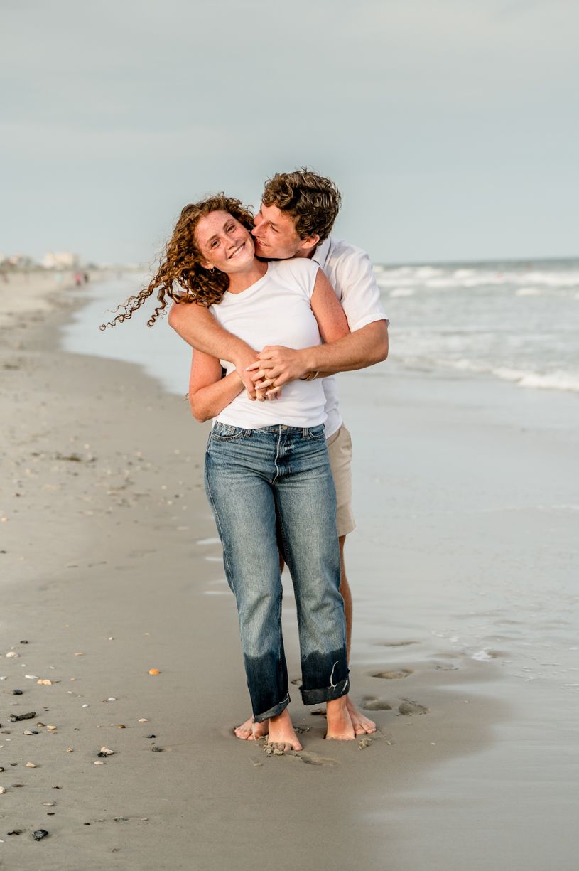 Couple shares intimate moment on beach at sunset.