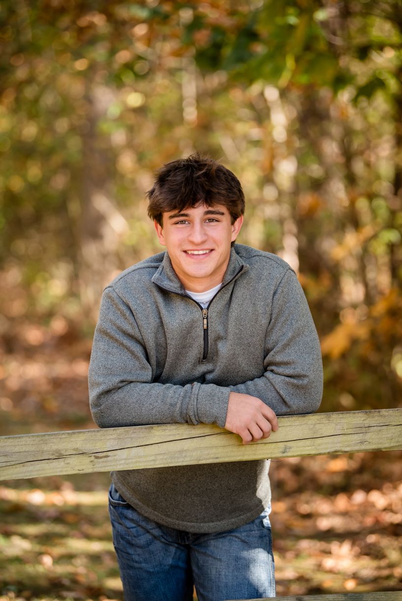 Casual outdoor portrait sequence of a senior guy wearing a grey sweater and jeans.