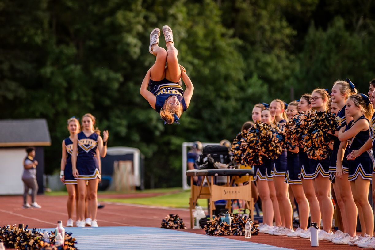 Cheerleaders performing routine sequence on athletic field.