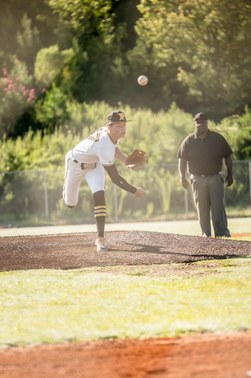 Baseball pitcher in motion on dirt mound during game sequence.