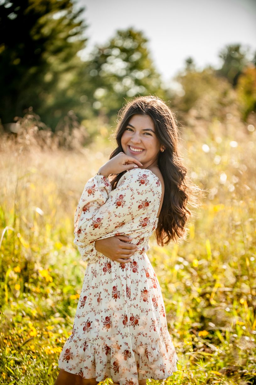 Senior girl in a wildflower field wearing a white floral dress.