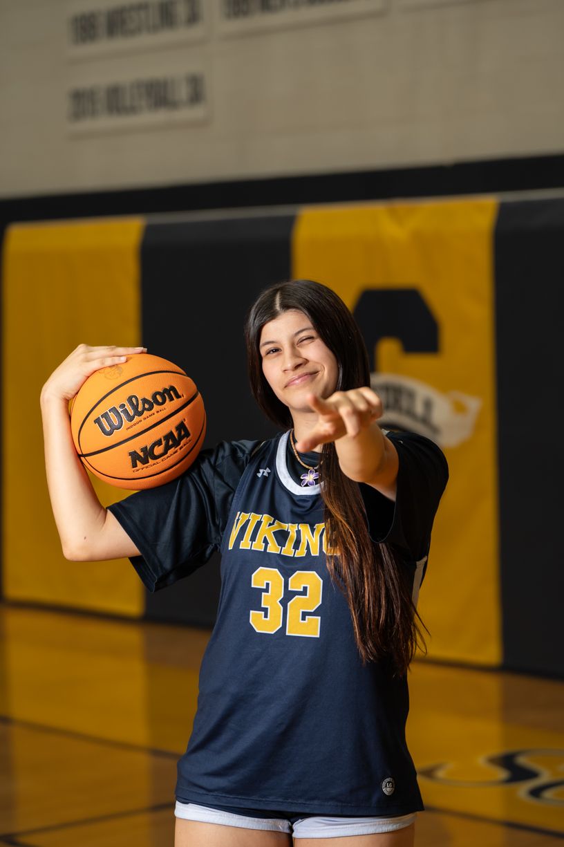 Basketball player poses with Wilson NCAA ball in navy Vikings jersey number 32.