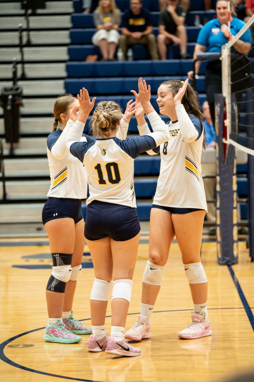 Volleyball players kneel on the court during a pre-game ritual.