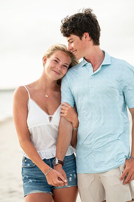 Couple in casual summer outfits sharing intimate moments on beach.