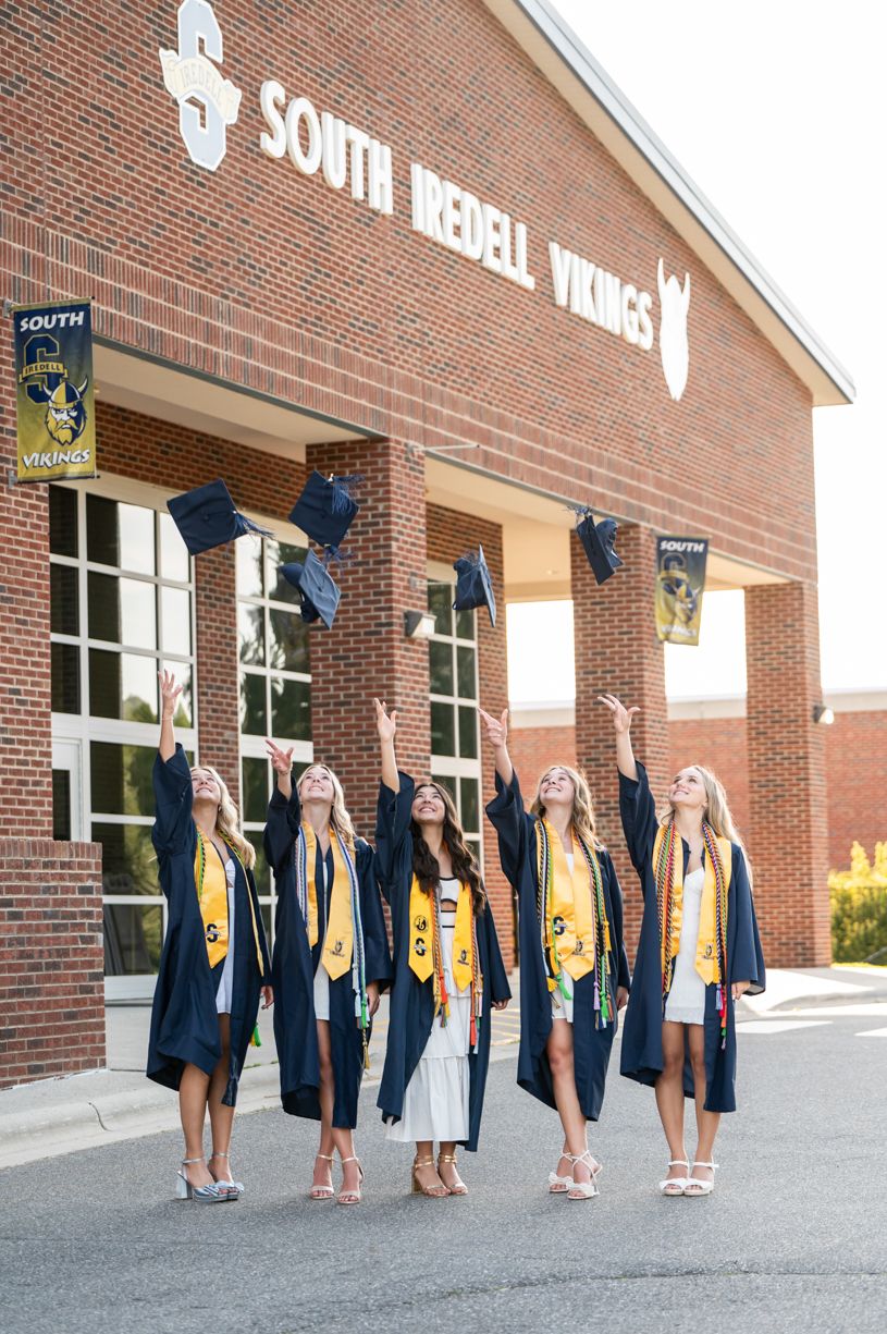 A group of graduates in blue caps and gowns standing outside a brick building.