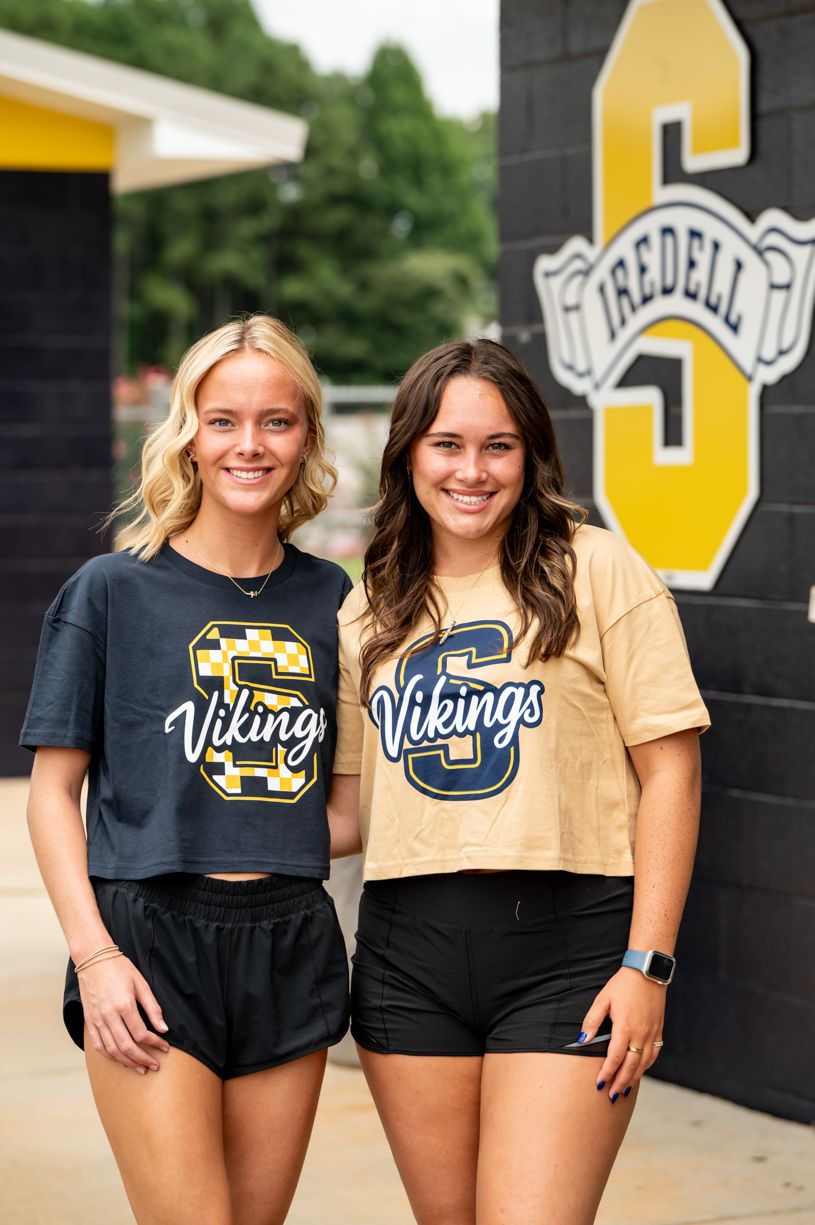 Students in Vikings team apparel pose together against a black and gold wall.