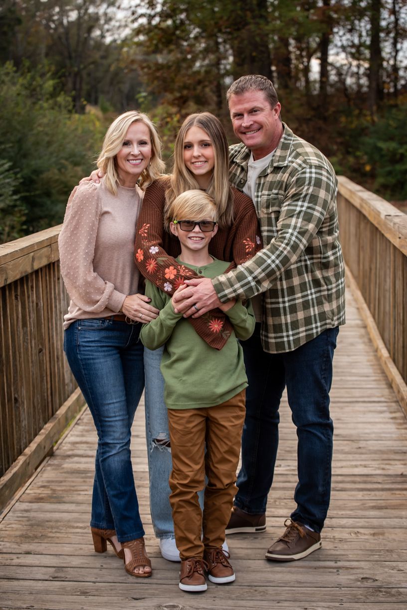Casual family portrait session on wooden bridge in autumn setting.