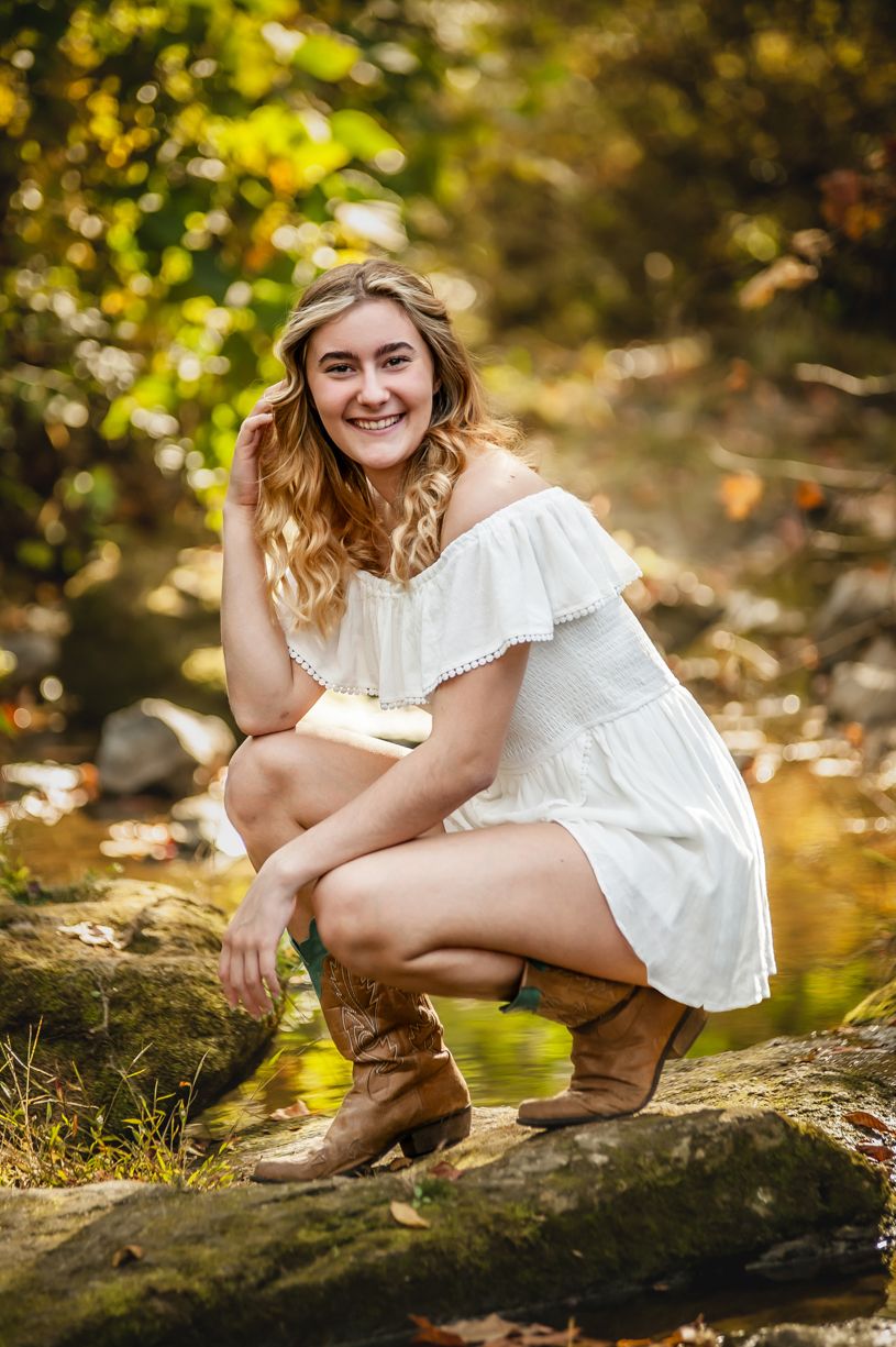 Outdoor autumn portrait session of a senior girl featuring white dress and natural lighting.