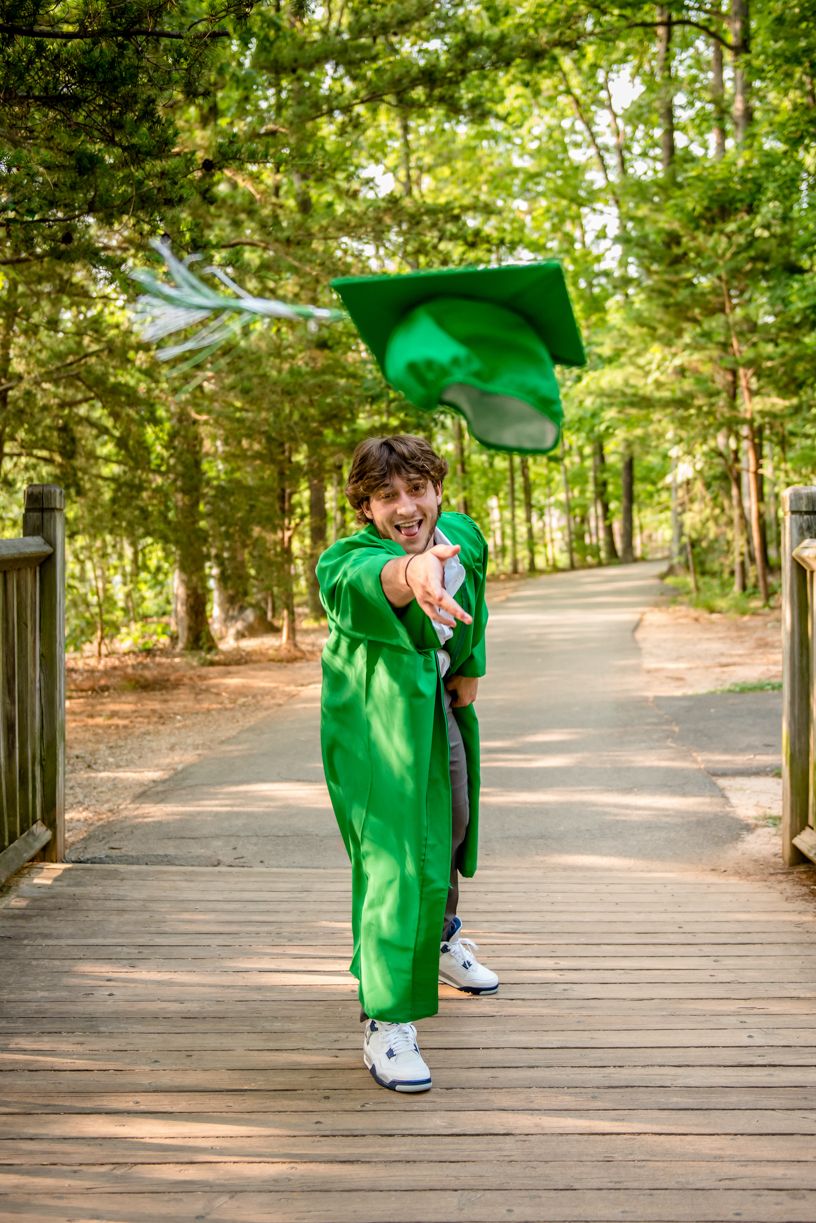Person in bright green outfit performing dance moves on wooden boardwalk through forest.