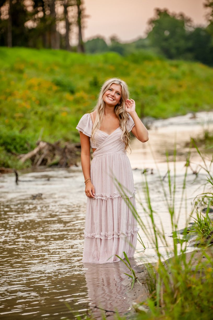 Senior girl poses creek-side with flowing dress and natural water elements.