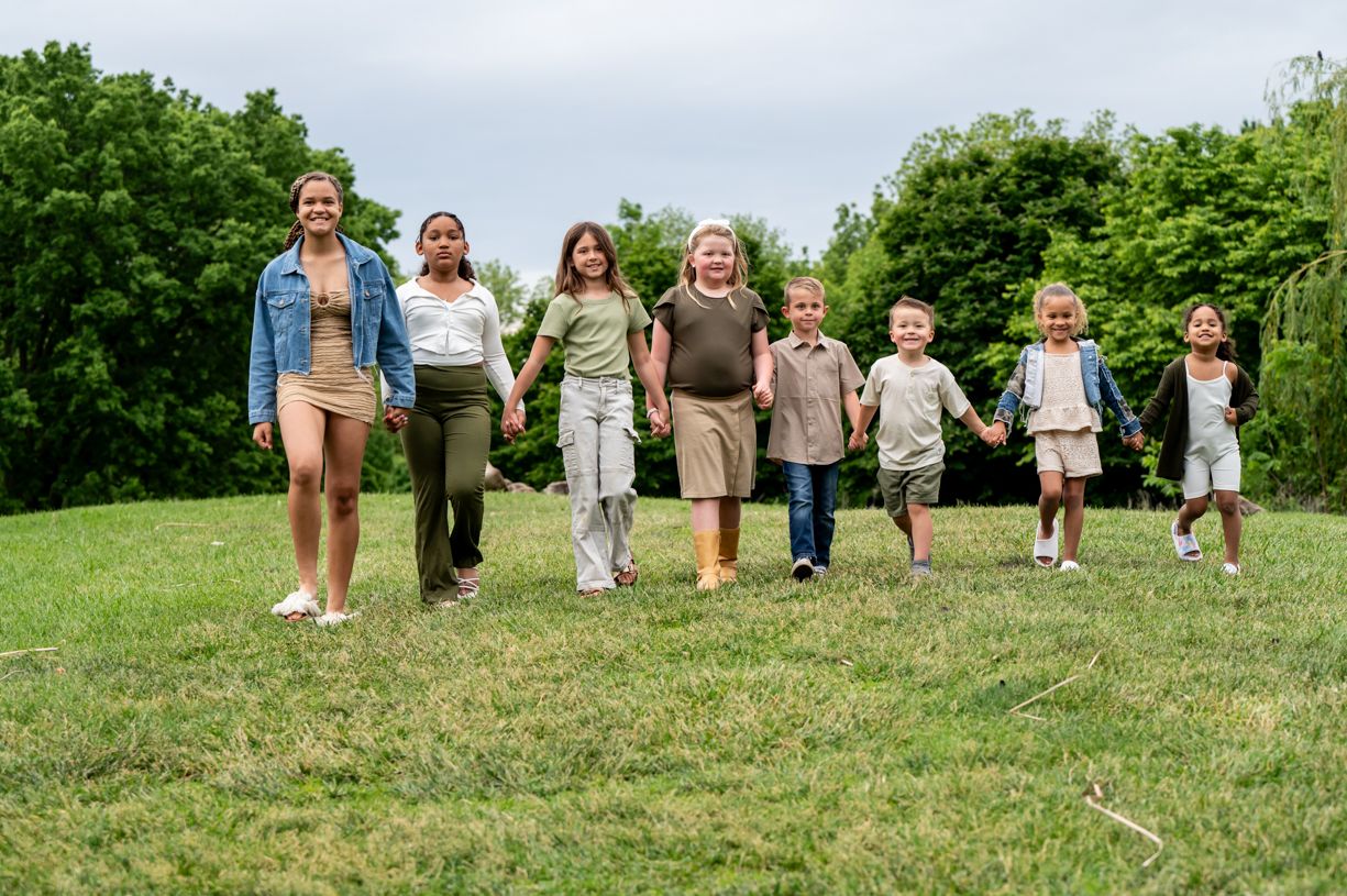 Group of kids running and playing together on a green hillside during summer.