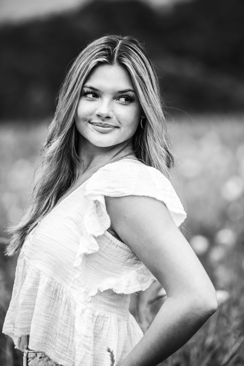 Black and white portrait of a senior girl in a natural outdoor setting with soft lighting.