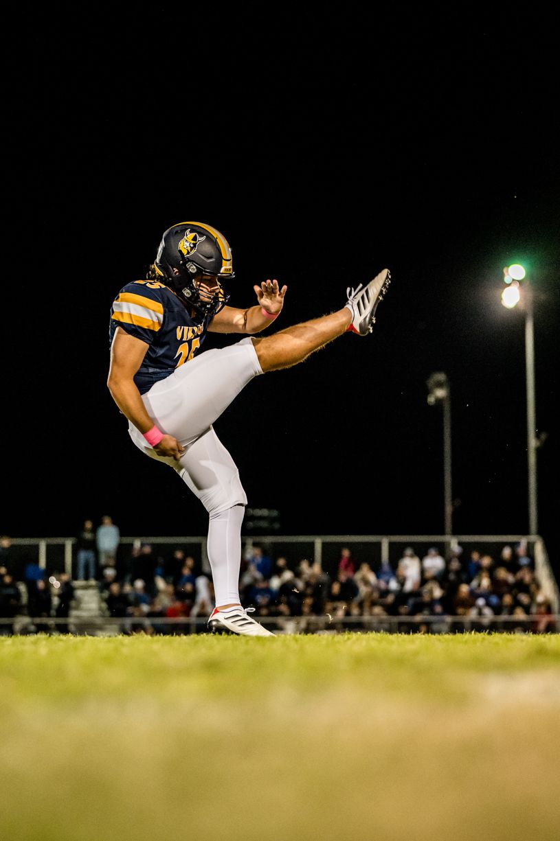 Football player executing high kicks in sequence during a nighttime game.