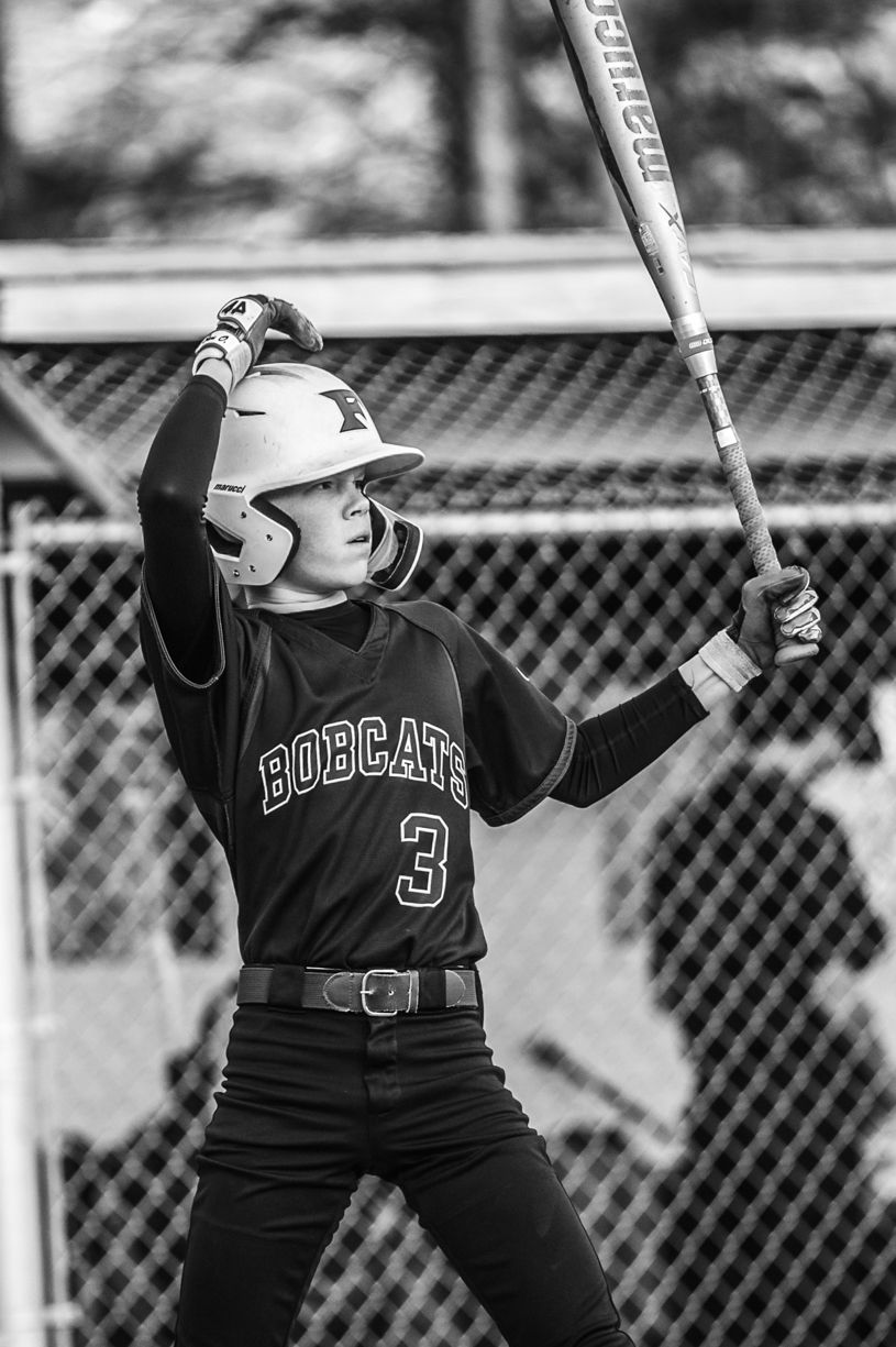 Baseball player in black uniform preparing to bat during game.