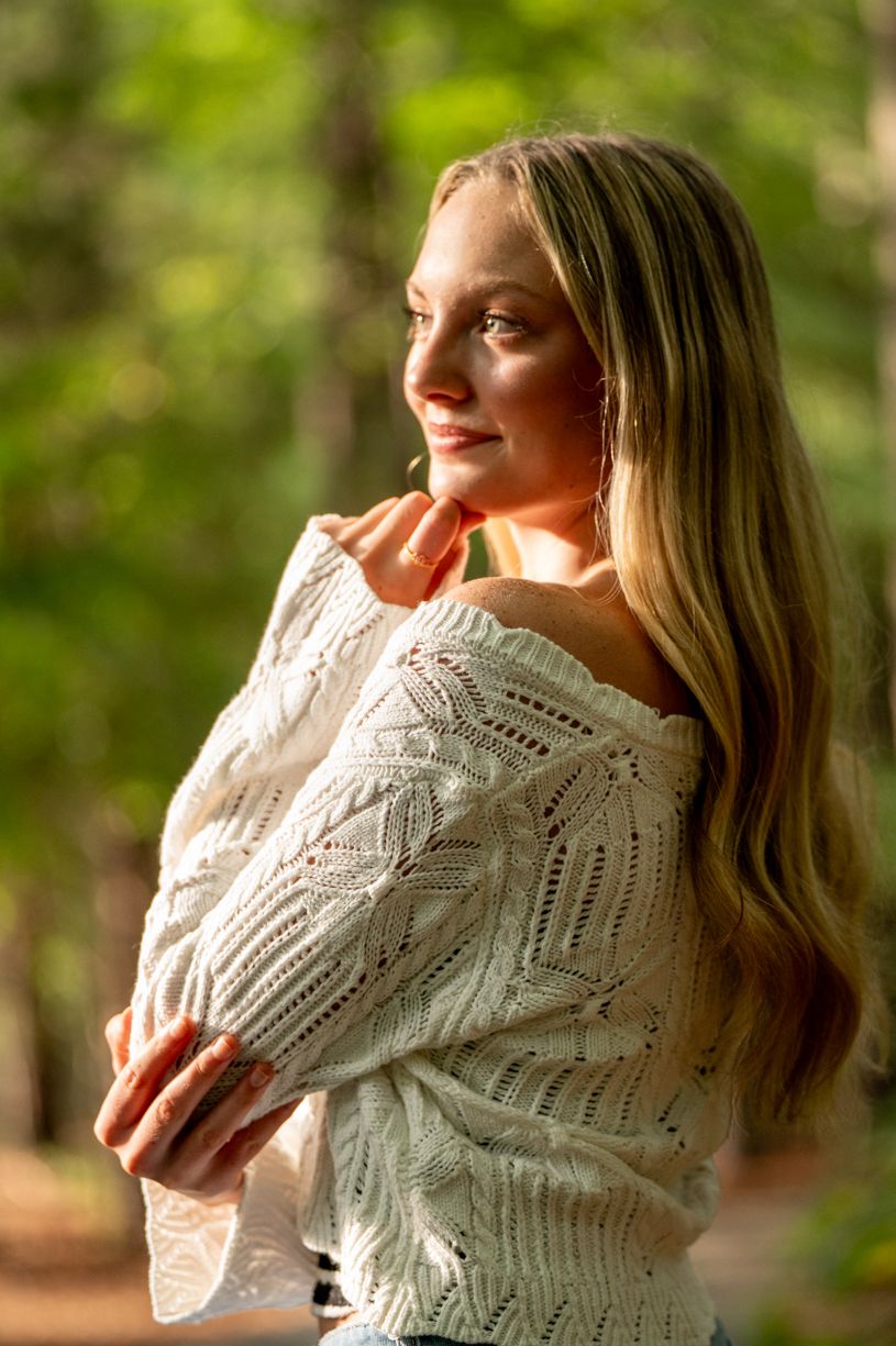 Cozy autumn senior girl wearing cream knit sweater in natural outdoor setting.