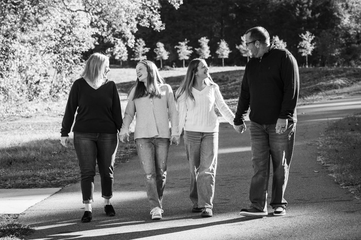 A group of people walking together on a tree-lined path in black and white.