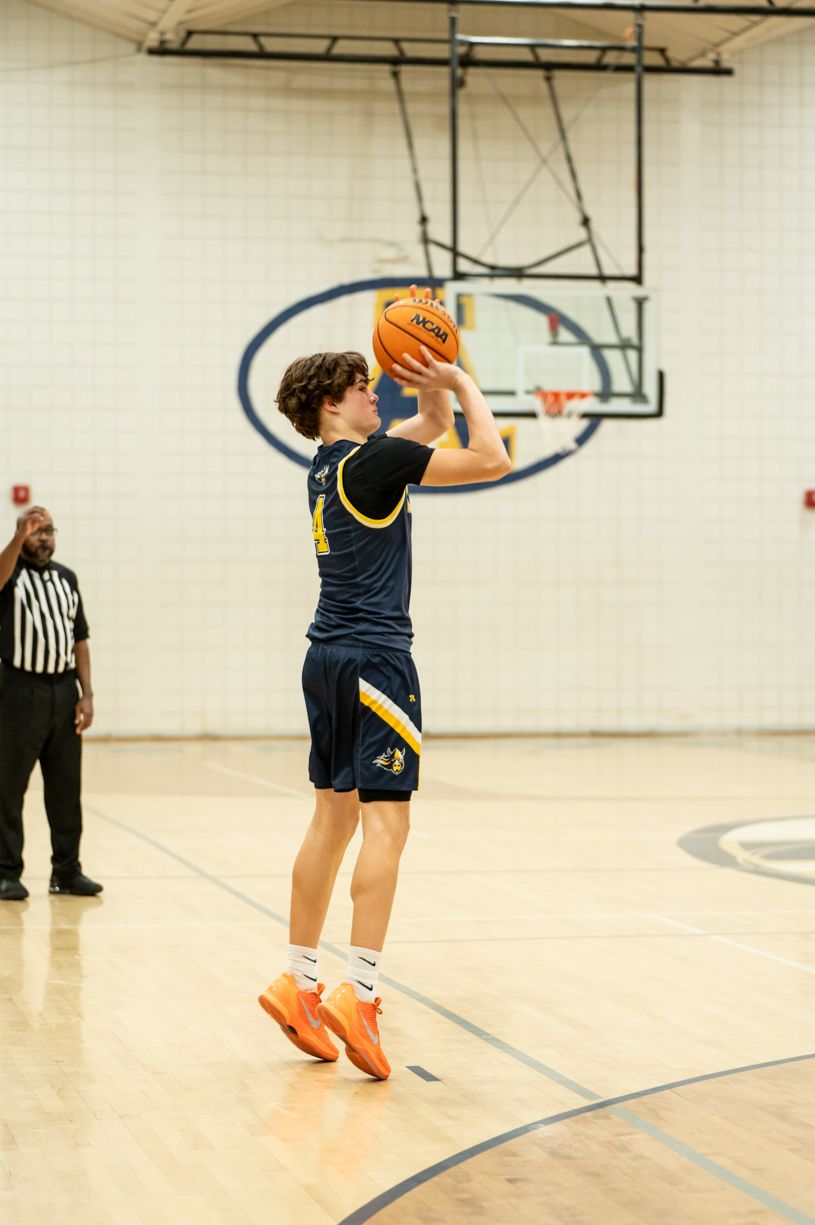 Basketball player taking a shot on indoor court.