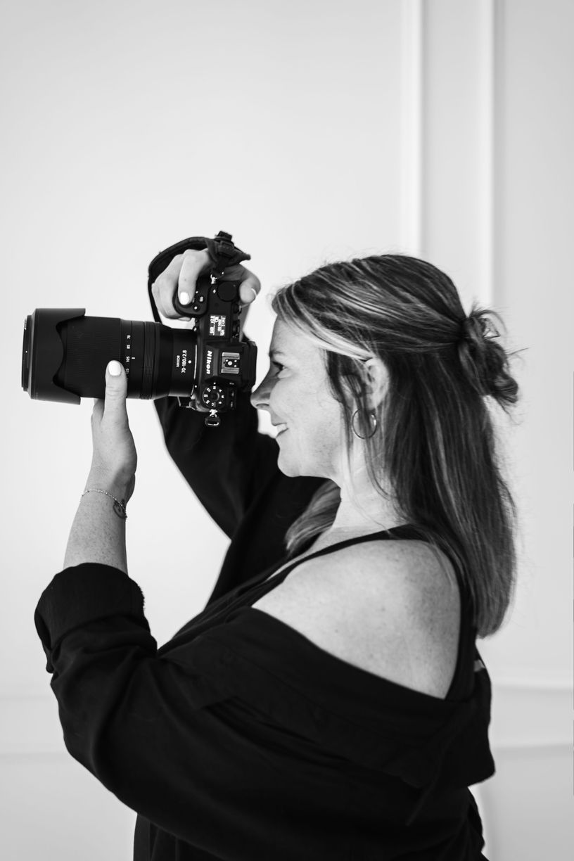 Side profile of photographer taking photo with professional DSLR camera against white background.