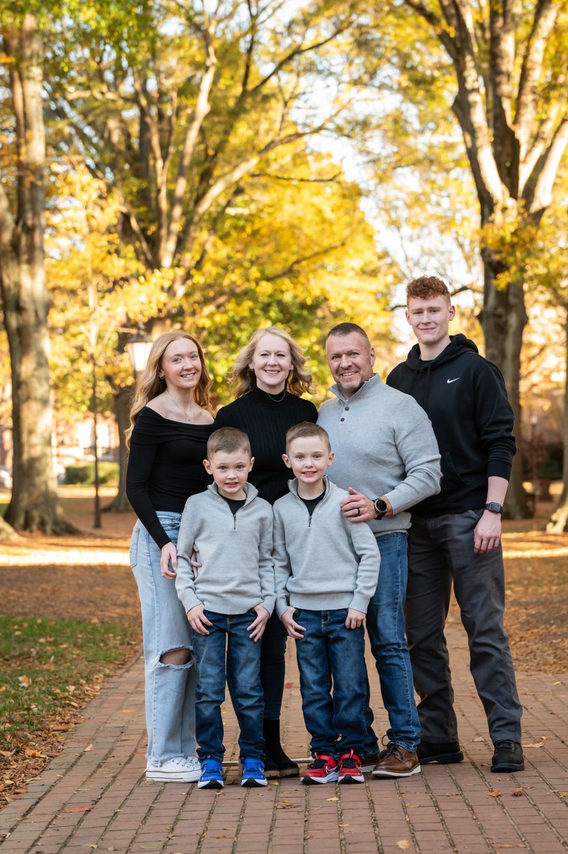 Family portrait in casual wear against autumn foliage background.