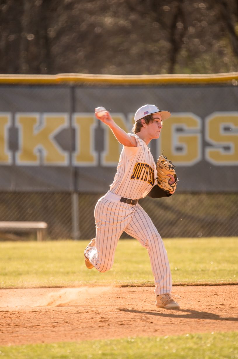 Baseball pitcher in pinstripes follows through on delivery during afternoon game.
