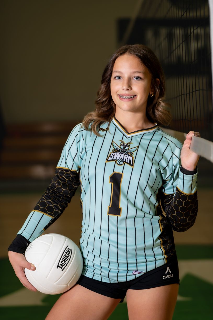 Youth athlete in light blue striped uniform holding a volleyball.