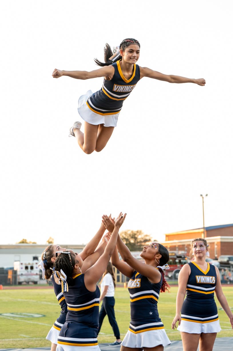 Cheerleaders performing stunts and formations on football field during game.