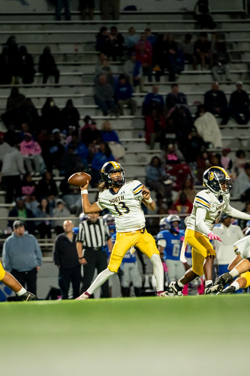Football player in yellow uniform throwing pass during night game.