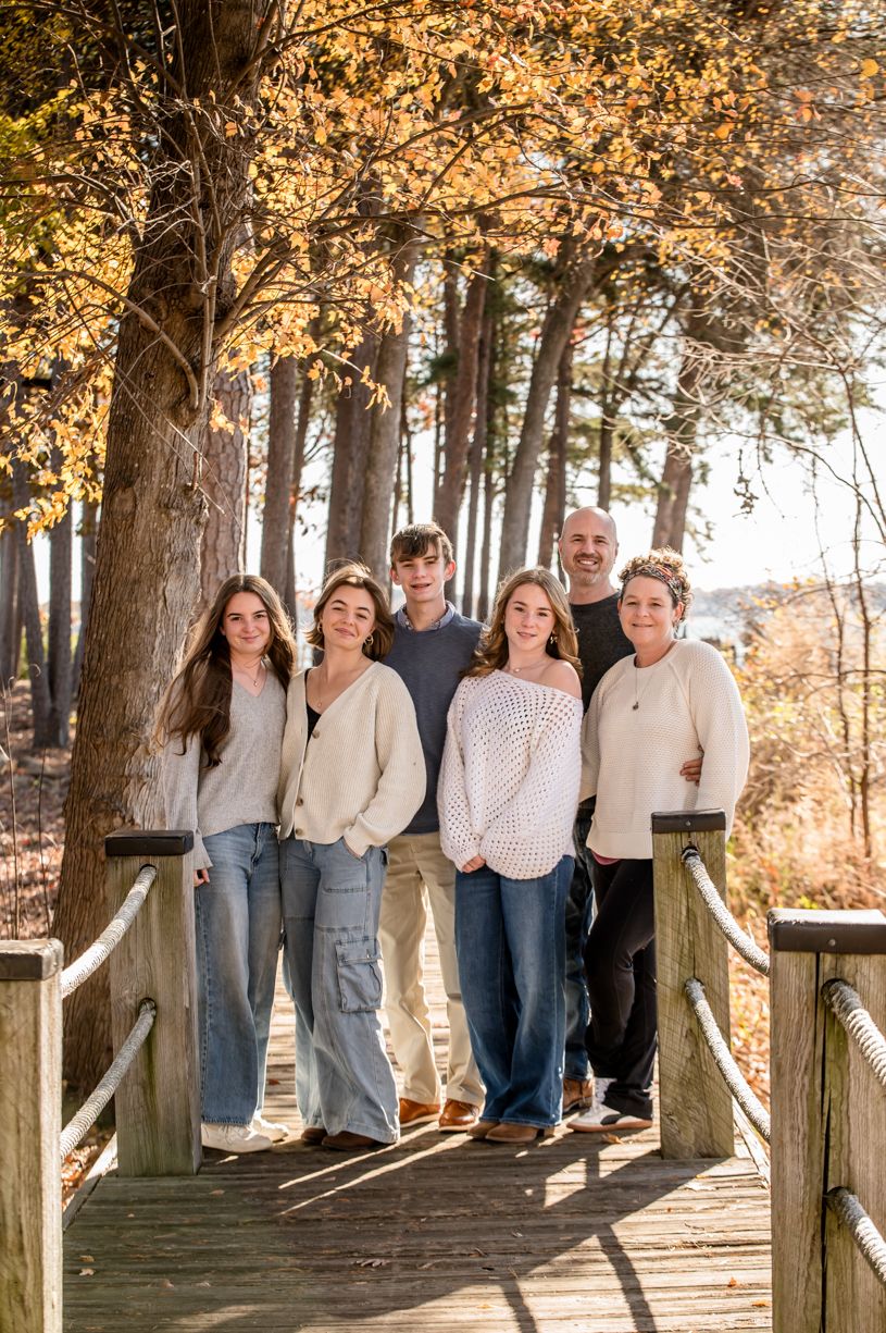Group portrait of people lined up along a wooden boardwalk surrounded by autumn trees.