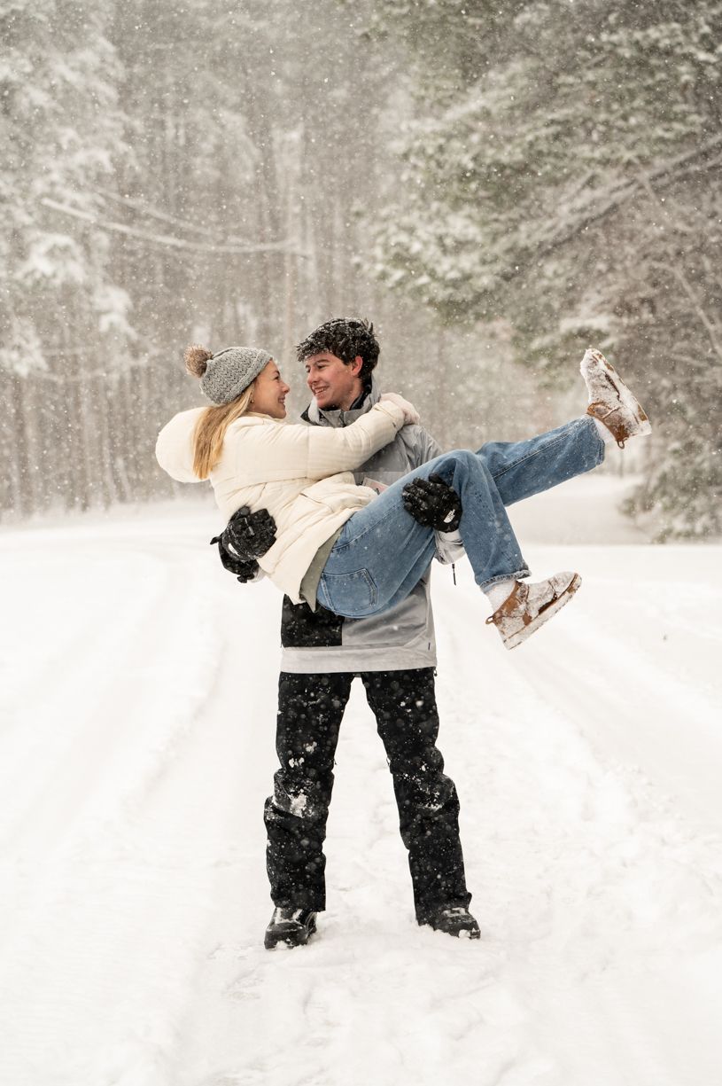 Playful couple in winter scene with one person lifting the other wearing ice skates.