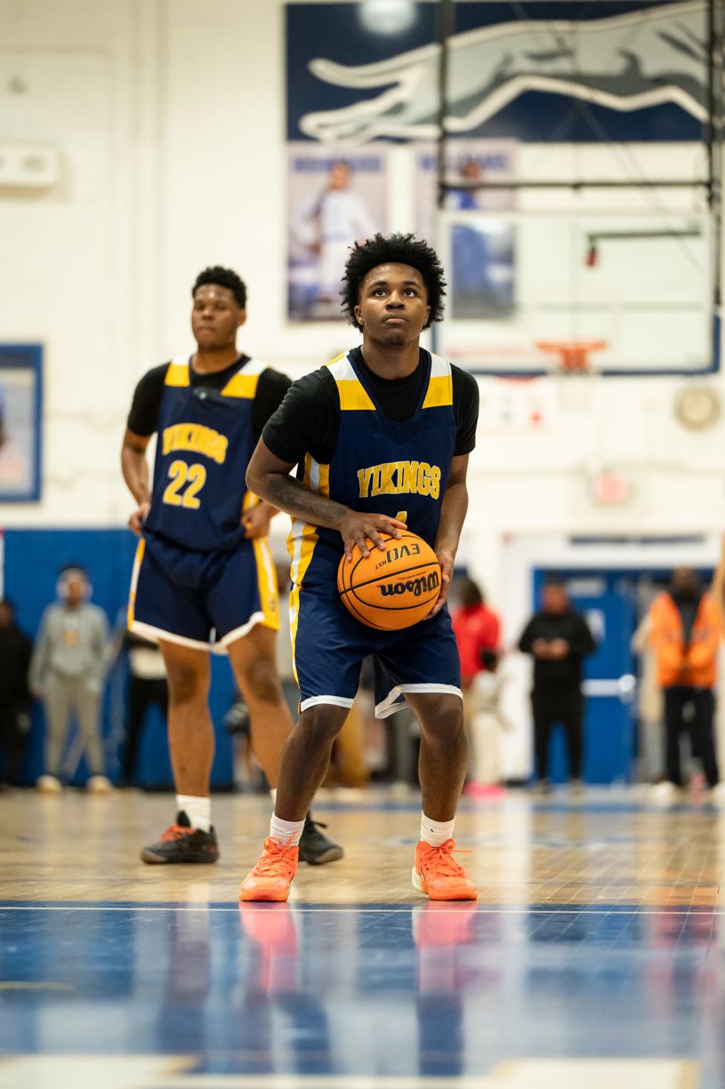 Basketball players in navy and yellow uniforms on court during game.