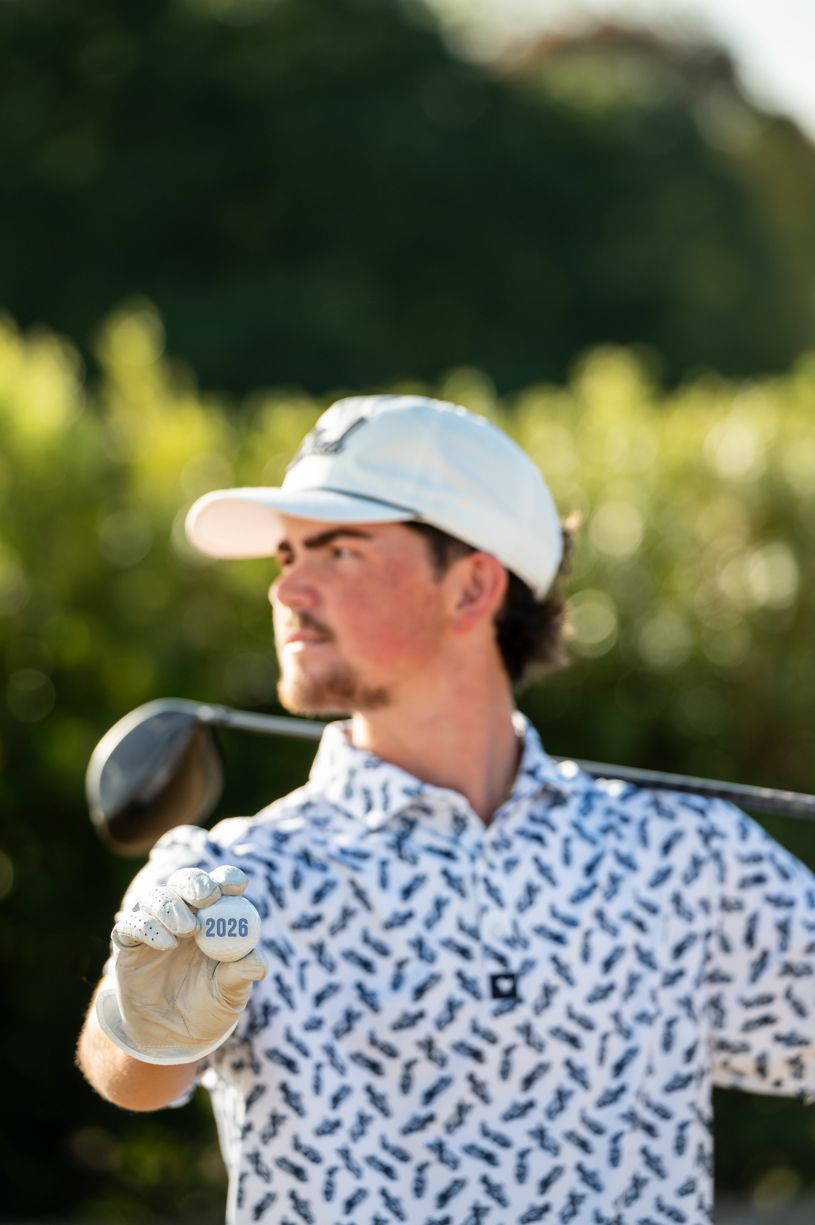 A senior golfer in a patterned shirt takes a swing on the course.