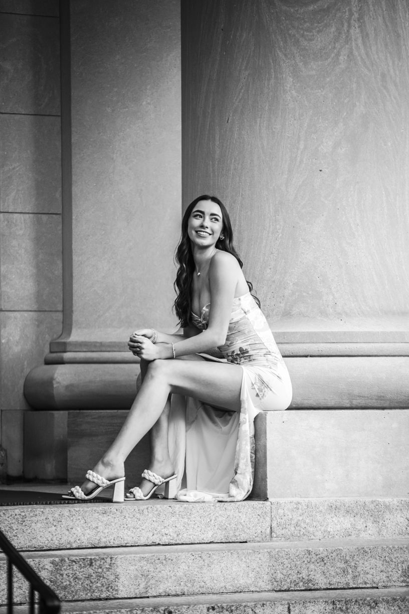 Black and white portrait of a senior girl sitting on stone steps.