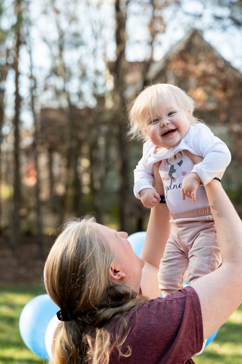 Joyful moments captured between parent and baby outdoors on a sunny day.